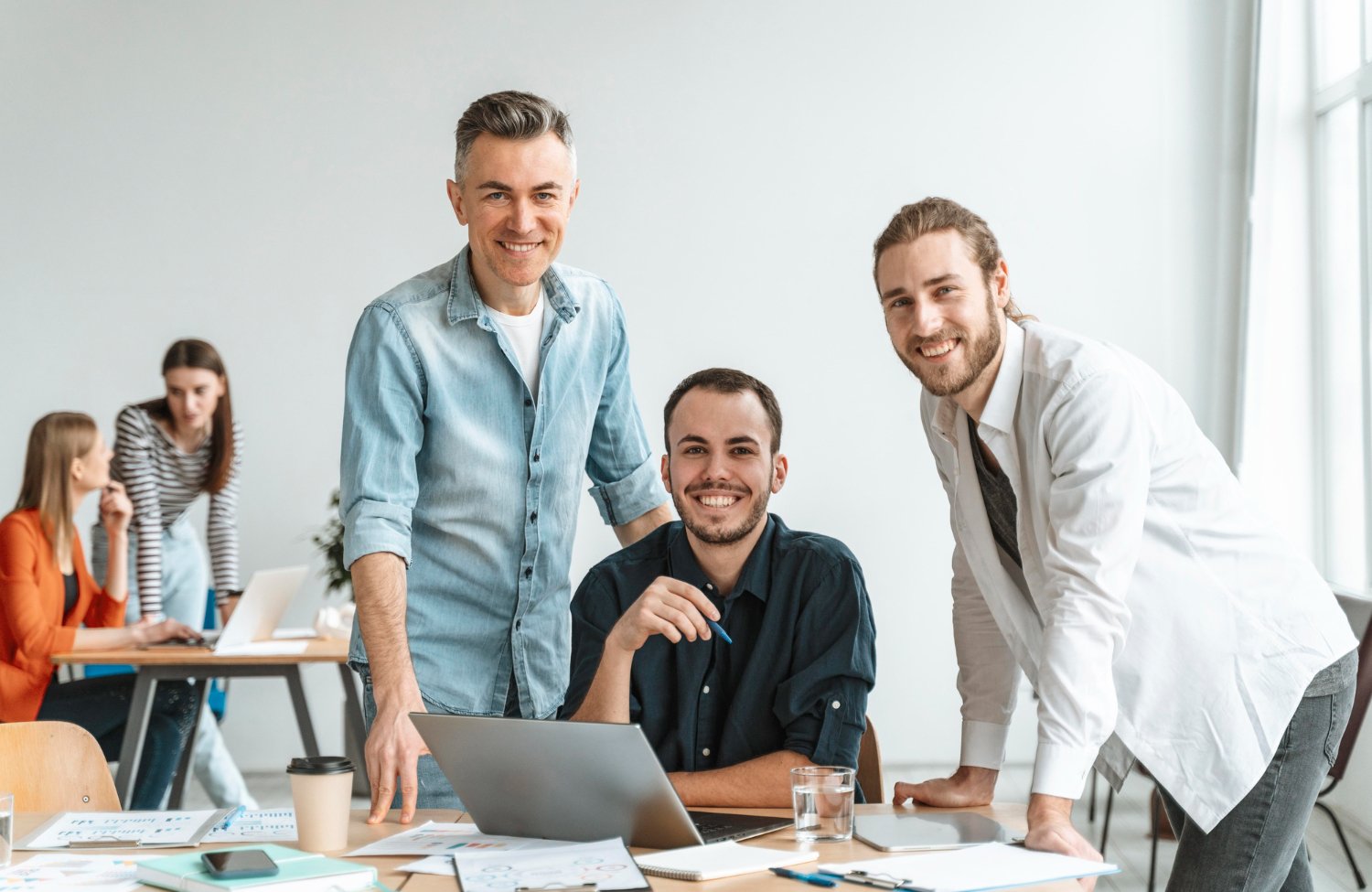 a group of men smiling at a laptop