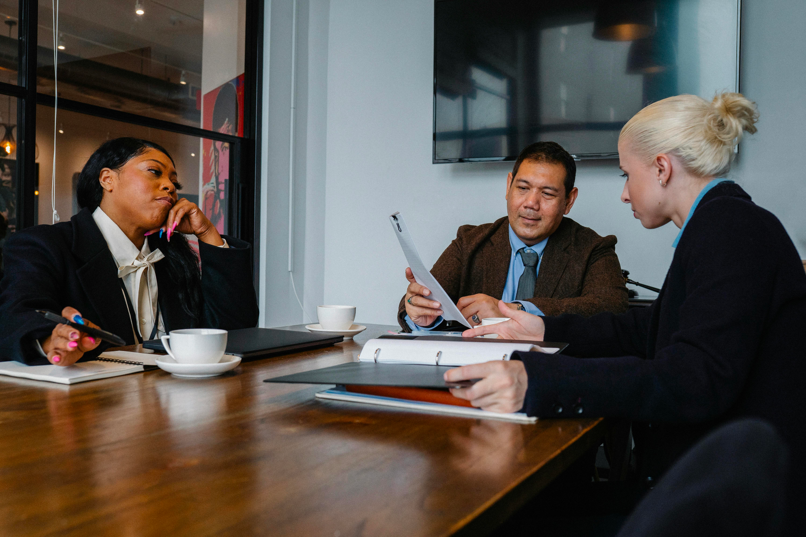 A group of people, with a financial advisor leading the discussion, are seated around a table, collaborating on strategic business decisions.